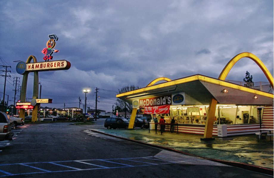 <div class="wp-block-group is-layout-flow wp-block-group-is-layout-flow"><div class="wp-block-group__inner-container"></div></div>



<div class="wp-block-columns is-layout-flex wp-container-core-columns-is-layout-9d6595d7 wp-block-columns-is-layout-flex">
<div class="wp-block-column is-layout-flow wp-block-column-is-layout-flow">
<p class="has-drop-cap">More so than the Big Mac, the Egg McMuffin, or those famous fries you just can't keep your hands off, the most iconic part of the McDonald's franchise and brand strategy as a whole is the "Golden Arches." Sure, their signature selections such as those above, Chicken McNuggets, the Filet-o-Fish, or even those delicious McDonald's hot apple pies are known and loved by millions across the globe. However, every company and brand strategy must start somewhere, even one that today that boasting over 3,600 individual restaurant locations with a strong, visible, successful presence in over 100 countries worldwide.&nbsp;</p>
</div>



<div class="wp-block-column is-layout-flow wp-block-column-is-layout-flow" style="flex-basis:48%">
<h3 class="wp-block-heading"><strong>Table of Contents</strong></h3>



<ol class="wp-block-list"><li><strong>Introduction</strong></li><li><strong>Refining and Defining a Brand Strategy</strong></li><li><strong>Two Golden Icons are Born</strong></li><li><strong>Brand Strategy for a New Look: "Speedee" Comes, and "Speedee" Goes</strong></li><li><strong>For Those About toKroc</strong></li><li><strong>Visualizing a Successful Brand Strategy: Look for the Arches</strong></li><li><strong>Billions and Billions Served and Earned</strong></li><li><strong>What's a McNugget?</strong></li></ol>
</div>
</div>



<p>So, hit the "drive-thru" quickly, grab a Quarter Pounder with Cheese or a McChicken sandwich and ice-cold Coke, and don't forget the fries. Then, settle in and take a "McJourney" with us back in time as we see how a food stand opened in a rural California community in 1937 and would eventually re-brand itself. Once they did, they were on the "McRoad" to becoming the most recognizable and iconic company, not only in the restaurant business but in any business across the entire world.</p>



<h2 class="wp-block-heading"><strong>Refining and Defining a <a href="https://www.blevinscreativegroup.com/services/" data-type="page" data-id="6">Brand Strategy</a></strong></h2>



<p>McDonald's rose to worldwide prominence, starting with a humble beginning in a moderately sized town, Monrovia, California, in 1937. It was then that this franchise would lay the foundation for its brand strategy. Not too long after implementation, they could boast of their "billions and billions served" on their signs out front of each location. However, that brand strategy started as a food stand located near the Monrovia airport. The stand upon its opening, by Patrick McDonald, was called "The Airdome." Initially, the biggest seller was hot dogs. However, as the stand saw modest business success, the menu would grow to include hamburgers, which cost ten cents apiece, and "all-you-can-drink" orange juice for just a nickel.&nbsp;</p>



<p>Fast forward to 1940, and Patrick's two sons, Maurice, and Richard would take over the reins of "The Airdome." The first step in their brand strategy is to bring the stand indoors and relocate it up the road about 40 miles to San Bernardino. The duo also renamed the restaurant at this point to "McDonald's Bar-B-Que," with a menu of some 25 items, most of which fell under the BBQ category.&nbsp;</p>



<p>However, by October 1948, the McDonald's brothers realized that most of their profits came from the sale of hamburgers, so they briefly shut down their "drive-in" type restaurant, despite enjoying some success, to streamline the menu for a re-opening. Once ready for the relaunch, the word "Bar-B-Que" would be dropped, and from here forth, the restaurant was known as McDonald's, and with a new, more convenient set up for preparation and service, they would re-open on December 12, 1948.&nbsp;</p>



<figure class="wp-block-image size-large"><img src="https://www.blevinscreativegroup.com/wp-content/uploads/2021/08/Arches-1024x766.jpg" alt="" class="wp-image-4364"/></figure>



<h2 class="wp-block-heading"><strong>Two "Golden Icons" are Born</strong></h2>



<p>Moving right along in our "McHistory lesson" on brand strategy. Now, as McDonald's enjoyed more and more success, by April of 1952, it was decided that a new look and a new building would be the next step in the evolution of the McDonald's brand strategy. At this point, the company's streamlined original menu had changed slightly, as it first included hamburgers, cheeseburgers, potato chips, soft drinks, and apple pie.&nbsp;</p>



<p>This switch would be significant because it would see the addition of milkshakes, which have remained a staple of the restaurant's menu ever since. Likewise, and even more so than the shakes, this would also be when chips were removed in favor of the now famous McDonald's French fries. There are two primary parts of the brand strategy that led to the brother's combination feeling that the new building would help them accomplish. These parts were to make the service and all-around dining experience more efficient and present a more "eye-catching" look to the restaurant.&nbsp;</p>



<p>Upon construction of the new McDonald's building, it was apparent that they had achieved the distinctive new look they set out for in their brand strategy. The new eye-pleasing features included surfaces of shiny, red, and white ceramic tile, stainless steel, brightly colored sheet metal, and glass. In addition, pulsating white, green, red, and yellow neon throughout the restaurant were new and bold additions to the décor.&nbsp;</p>



<p>However, the one significant aesthetic addition that no one could have ever imagined would become a symbol recognized across six continents at the time. This addition was two 25-foot yellow sheet metal arches, at the time trimmed in neon. Even in the design stage, these were referred to in a term we all would come to know, the "Golden Arches."</p>



<h2 class="wp-block-heading"><strong>Brand Strategy for a New Look: "Speedee" Comes, and "Speedee" Goes</strong></h2>



<div class="wp-block-image"><figure class="alignright size-large is-resized"><img src="https://www.blevinscreativegroup.com/wp-content/uploads/2021/08/McDog-scaled-e1629831481502-942x1024.jpg" alt="Brand Strategy it's a dog eat dog world" class="wp-image-4370" width="423" height="460"/></figure></div>



<p>The improved efficiency, along with the desire to become more visible, had become the two-pronged brand strategy aimed at the expansion and was a significant step in building the "new" McDonald's brand. Regarding the "new look," at first, the now-iconic arches were not necessarily seen yet as the company's primary logo. The first new symbol moving forward was to stress the new, faster, and more efficient "Speedee Service System." This would be a "pudgy character" wearing a chef's hat, whose face somewhat resembled a hamburger named Speedee. The winking eye of Speedie was said to have been a tip of the cap and represent the faster service than their food facility. However, though the cartoonish "Speedie" was the original logo, so to speak, the McDonald's brothers had initially thought of the "arches" as to catch the attention of bypassers. Hmmm…maybe, just maybe, they were onto something.</p>



<p>As with any <a href="https://www.blevinscreativegroup.com/storytelling/this-is-your-brand-any-questions/" data-type="post" data-id="3864">strong brand strategy</a>, there are points where the company's that succeed realize they must evolve or change for the better. In the case of McDonald's, this change would fully take place when in 1961, Ray Kroc purchased the business from Maurice and Richard. Once Kroc was the owner, he again called for modifications to the brand identity. These would be ones that would change the restaurant industry and ones that would reach every corner of the Earth.</p>



<h2 class="wp-block-heading">That's <strong>Kroc</strong> with a 'k' Like 'crocodile' but not spelled that way (As Mr. Knofler puts it in his tribute song to Ray Kroc; "Boom, Like That")</h2>



<figure class="wp-block-embed alignright is-type-video is-provider-youtube wp-block-embed-youtube wp-embed-aspect-16-9 wp-has-aspect-ratio"><div class="wp-block-embed__wrapper">
https://www.youtube.com/watch?v=0sYK2RwH5E8
</div><figcaption>"Boom, Like That" is the first single from Mark's album Shangri-La released in 2004.</figcaption></figure>



<p>The brothers feared that making risking a national venture could change their thriving local business. Thus, Kroc would offer to help more with <a href="https://www.blevinscreativegroup.com/storytelling/this-is-your-brand-any-questions/" data-type="post" data-id="3864">brand strategy</a> and take on a significant portion of the responsibility in this expansion. When leaving his discussions with the McDonald's boys, he had headed home to just outside of Chicago is given the rights to set up McDonald's franchises all across the United States.&nbsp;&nbsp;</p>



<p>The initial relationship between Ray Kroc and the McDonald's began in 1954 when he had visited them upon hearing they used eight Prince Castle brand milkshake machines, which were the same brand he was selling. When Kroc showed up at the San Bernardino location, McDonald's restaurants had grown to include six franchises. Believing that this restaurant model had limitless potential, Kroc suggested that they franchise all over the country as part of his brand strategy.&nbsp;</p>



<p>The first McDonald's that Kroc would open was near his home in De Plains, IL, in 1955. He would call on a professional, a master painter, Eugene Wright. Kroc asked this expert on color schemes and came up with an idea for his restaurants. Wright would return with the white and yellow with a dark brown and red trim color pattern that has pretty much been synonymous with McDonald's ever since. Once his Des Plains location was opened, Kroc began looking for franchisees.&nbsp;&nbsp;</p>



<p>Getting business advice and assistance with the brand strategy from the former VP of finance for the Tastee Freeze company, Harry Sonneborn, by 1958, the total of McDonald's restaurants would grow to 34 in the U.S. Just a year later, Kroc enlisted Sonneborn as President and CEO of McDonald's. In that year alone, 68 new franchises opened across the country, bringing the total to 102 locations.</p>



<h2 class="wp-block-heading"><strong>Visualizing a Successful Brand Strategy: Look for the Arches</strong></h2>



<p>In 1960, the company's brand strategy called for a new advertising campaign. This campaign for McDonald's would be implemented and, although not known at the time, would be the most crucial change in establishing their brand in company history. This would be the most significant part of the McDonald's brand strategy ever, as they unveiled a new slogan. It&nbsp;&nbsp;was "Look for the Golden Arches." There was an immediate boost in sales as this campaign went public, and in 1962, "Speedie" would be no more, and the arches seen outside the restaurants would take the form of a letter "M," and the golden arches logo was born.&nbsp;</p>



<p>As the early 1960s moved along, the arches would be the launching pad to see the McDonald's rocket to new heights. The timing would coincide with the national growth of the automobile and the addition of the interstate highway system. However, all was not well between Kroc and the two McDonald's brothers despite the success. This was due to a stark contrast in the company's two sides' brand strategy and vision. The difference of opinion eventually became unbearable, leading to Kroc offering to buy out the brother partners.</p>



<p>The brothers would take $2.7 million ($21.6 in today's dollars), and Kroc bought them out. Following this in 1965, the company went public, and in doing so, their basing the new brand strategy on listening to what the customer wanted would pay huge dividends. This saw several staples of their menu to this very day introduced throughout a several-year period. These would include "Filet O Fish" (1962) and the now legendary Big Mac in 1968. That would also be the year Sonneborn stepped down, and Kroc himself took over as President and SEO.&nbsp;</p>



<p>With the nation now "driving-thru" and "looking for the arches," Kroc again evolved his brand strategy with the time's coming up with one of the most well-known marketing campaigns in the history of any business, as the golden arches would accompany a new slogan, "You deserve a break today." Shortly after that campaign launched, the expansion of McDonald's found the restaurant opening its 1,000<sup>th</sup>&nbsp;location and finally being present in all 50 United States.</p>



<figure class="wp-block-image size-large"><img src="https://www.blevinscreativegroup.com/wp-content/uploads/2021/08/McHungry-1024x683.jpg" alt="Brand Strategy to serve billions and billions" class="wp-image-4374"/></figure>



<h2 class="wp-block-heading"><strong>Billions and Billions Served…and Earned</strong></h2>



<p>The decade of the 1970s would bring more fresh brand strategy ideas. Thus came even bigger and better things for McDonald's. In 1972, the company would, for the first time, pass $1 billion in annual sales. By mid-decade, in 1976, that total would go over $3 billion, and as the signs in front of each location would tout, they had served upwards of 20 billion hamburgers. Also, during this stretch, breakfast became part of the brand strategy. Then another legendary sandwich and fast-food innovation were developed. The Egg McMuffin came in 1972, and the expanded world of fast-food breakfast was not far behind.&nbsp;</p>



<p style="font-size:24px">In 1977 McDonald's would create a full breakfast menu, and in ten years, by 1987, 25 percent of all breakfast eaten out in America was eaten at a McDonald's. Also, the drive-thru window was added at locations in 1975, and in 1979 yet another iconic part of the McDonald's brand was introduced, and children nationwide began asking their parents for a "Happy Meal."</p>



<p>Sure, all of these new marketing ideas would be a massive part of the McDonald's brand strategy moving forward. But the menu would not be all that would see changes that would come to help define this brand. So in the early part of the decade, Kroc, just as he had for the color scheme, called on an expert in helping to come up with a new look for the restaurants.&nbsp;</p>



<p>What was then developed was the iconic four-sided, natural brick and cedar mansard roofs that practically everyone in the world is now familiar with. Maybe the most prominent brand strategy development of the 70s, though, was the beginning of McDonald's global expansion. Countries around the globe around mid-decade would, for the first time, see the golden arches as they would eventually become one of the most recognizable brand logos ever created. Yet, somehow, this was all still just the beginning of the growth of the McDonald's brand</p>



<p>As with any successful brand strategy, the constant we have seen in McDonald's growth the ability to change with the times and keep their finger on the pulse of what the public and the customer want to see. So, keeping course with its brand strategy to unveil new products that would become world-famous, with the start of the 1980s came the debut of Chicken McNuggets.&nbsp;</p>



<h2 class="wp-block-heading"><strong>What's a McNugget?</strong></h2>



<p>While it spurned many late-night talk jokes from the name, their popularity was off the charts, and they remain a top seller today. Heading forward and continuing to evolve with the times as they have since Kroc to over the reins of the franchise, McDonald's in the 1990s would introduce another soon-to-be favorite, the ice cream McFlurry.&nbsp;</p>



<p>But the brand strategy not just about food items, changes in design to their restaurants, or just the worldwide expansion that kept pushing the McDonald's brand above and beyond the competition. The creative genius behind the brand strategy and marketing would again unveil a strategy for a campaign that would again strike gold starting in 2003 behind the slogan, "I'm Lovin' it." It is the continuous ability to stay on top of the pulse of the public that genuinely pushed them to the point of becoming more than just a chain of fast-food restaurants and becoming a part of pop culture and a worldwide entity.&nbsp;</p>



<div class="wp-block-image"><figure class="alignright size-large"><img src="https://www.blevinscreativegroup.com/wp-content/uploads/2021/08/McDonalds_near_Circular_Quay_Sydney_CBD-1024x760.jpg" alt="McDonalds's" class="wp-image-4376"/></figure></div>



<p>Behind all of that, from almost the beginning, has been the iconic yellow arches that if you drive down about any highway in American or in the world for that matter, you can see sticking out above the competitors from a distance. Seeing the arches high above the landscape not only gives you an early start at deciding where to eat on a road trip, but it also serves as a symbol. A symbol that was initially developed in the early 1960s but has continued to climb higher and higher above the proverbial "other rooftops" with no end to that perpetual ascent in sight.</p>



<small><p>(cover photo by: Photo by Bryan Hong of The <a href="https://en.wikipedia.org/wiki/Oldest_McDonald%27s_restaurant" rel="nofollow">oldest operating McDonald's</a> restaurant was the third one built, opening in 1953. It's located at 10207 Lakewood Blvd. at Florence Ave. in Downey, California.</p></small>